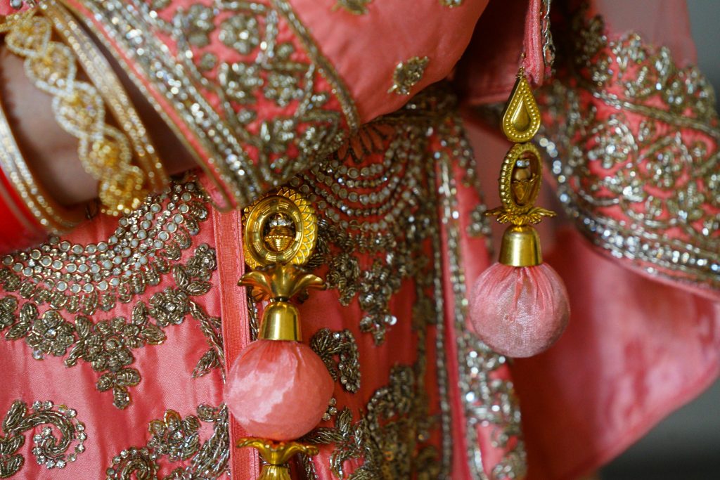 Close-up of detailed embroidery and embellishments on pink traditional attire.